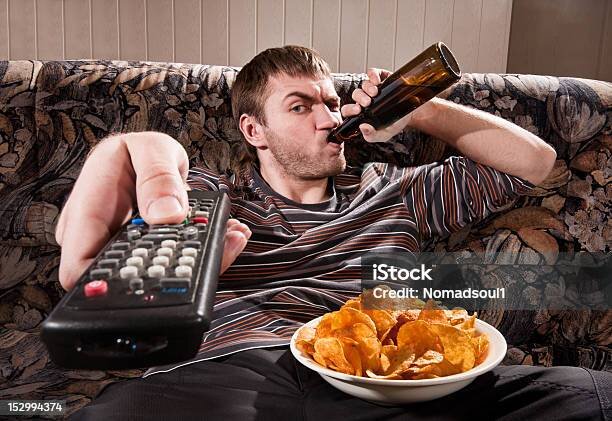 man-sitting-on-the-couch-holding-a-remote-and-a-beer-bottle.jpg