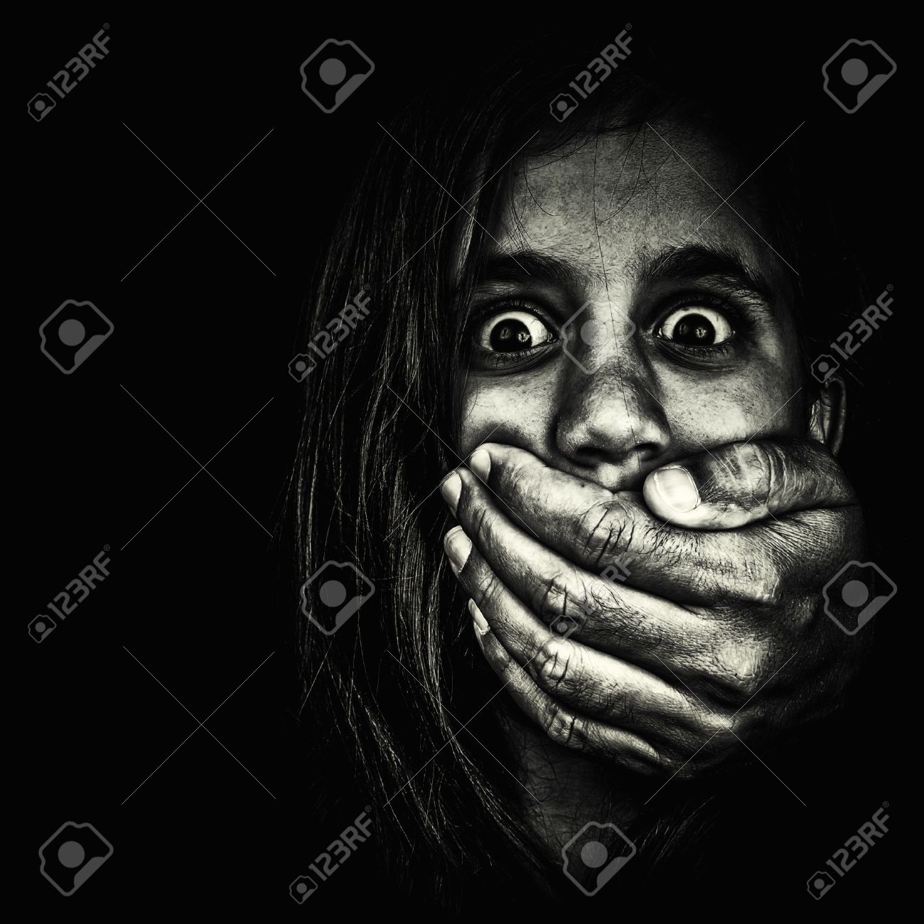 16576029 horror portrait of a very frightened girl with an adult hand covering her mouth isola