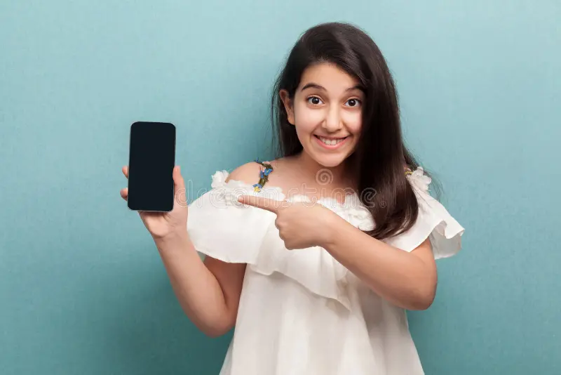 Portrait happy beautiful teenager girl white dress standing holding phone pointing finger dis