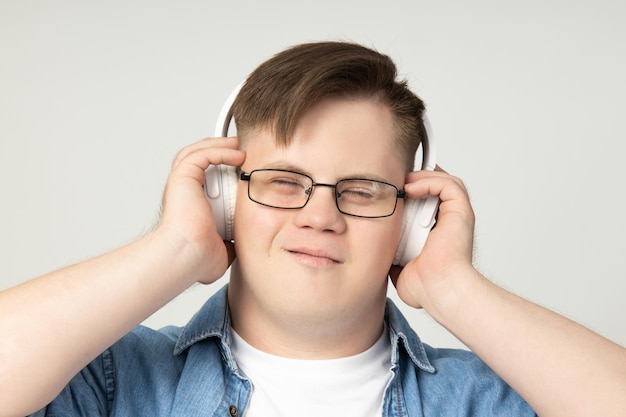 Smiling young man with down syndrome wearing glasses listening music headphones 185193 136109