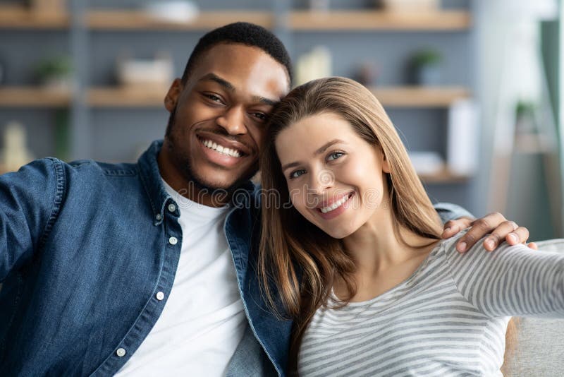 Portrait cheerful young romantic interracial couple taking selfie together home closeup happy 