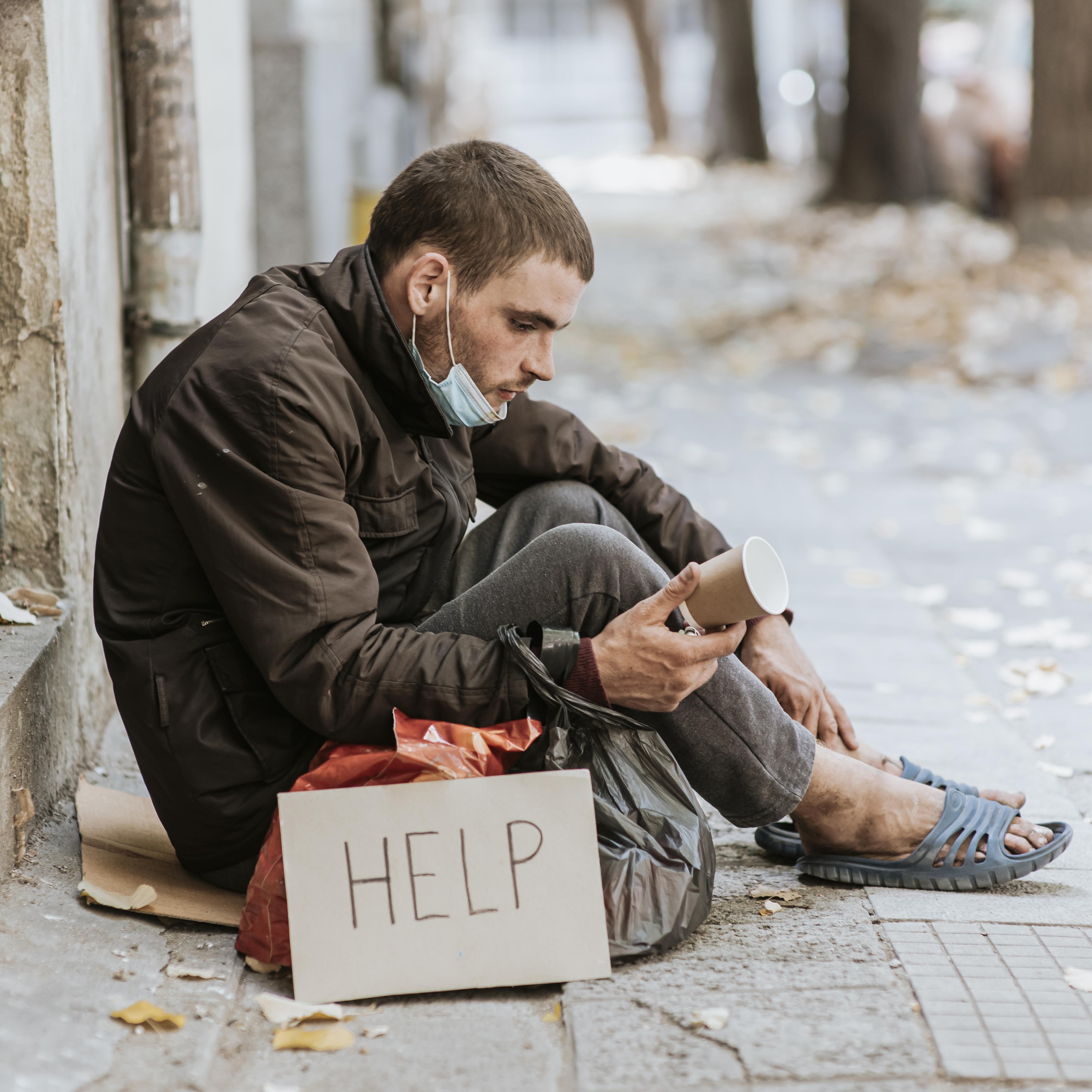 Side view homeless man outdoors with help sign cup