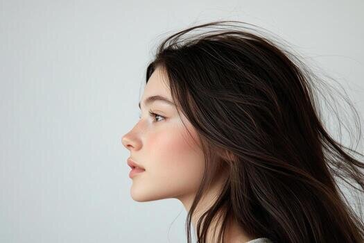 Profile shot of a beautiful young brunette with wind swept hair against a white backdrop photo