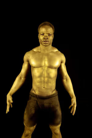 14610558 a man who is painted gold standing with an intense expression on his face