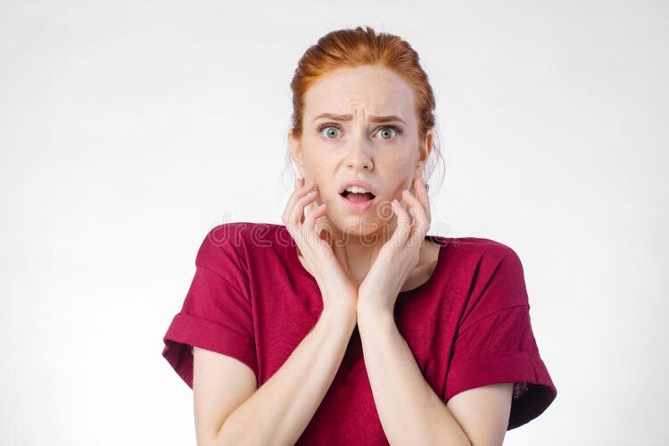 Shocked woman looking camera open mouth touching head redhead wearing red shirt over white bac