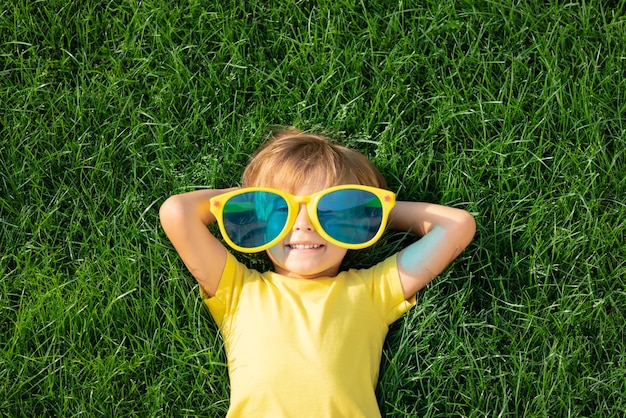 Happy child playing outdoor spring park kid lying green grass earth day ecology concept top vi