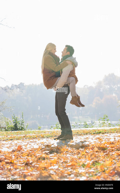 young-man-lifting-woman-in-park-during-autumn-HNEM7E.jpg